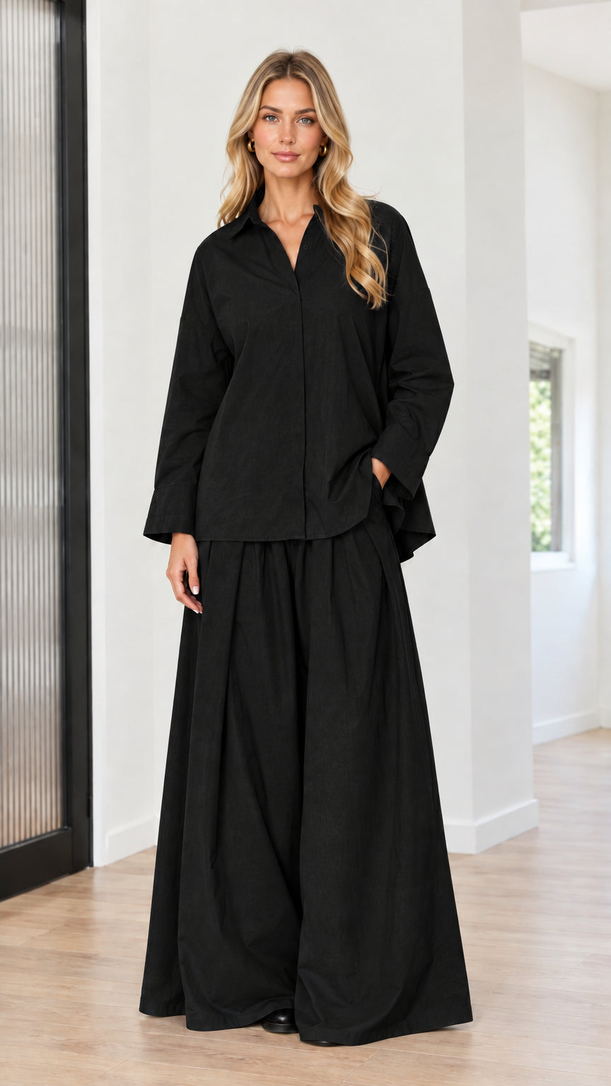 Model wearing black two-piece collared button-down shirt and pleated wide-leg pants set
