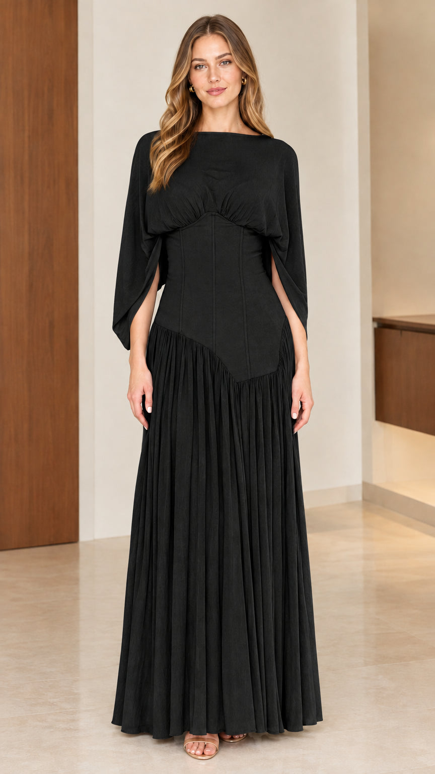 Full-length front view of model wearing black corset waist pleated maxi dress