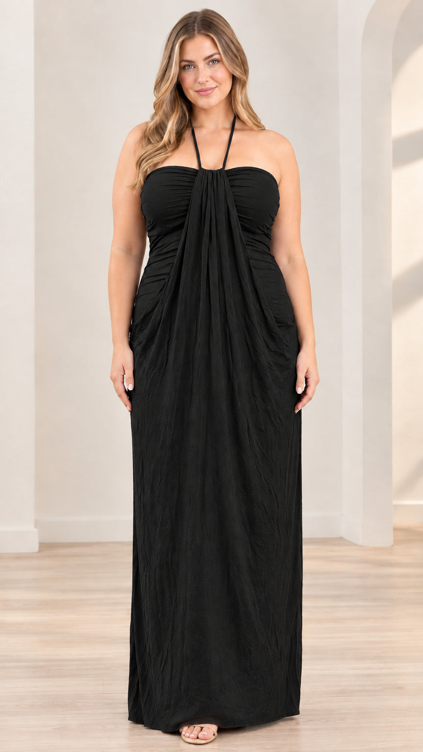 Front full-length view of model wearing black halter draped maxi dress