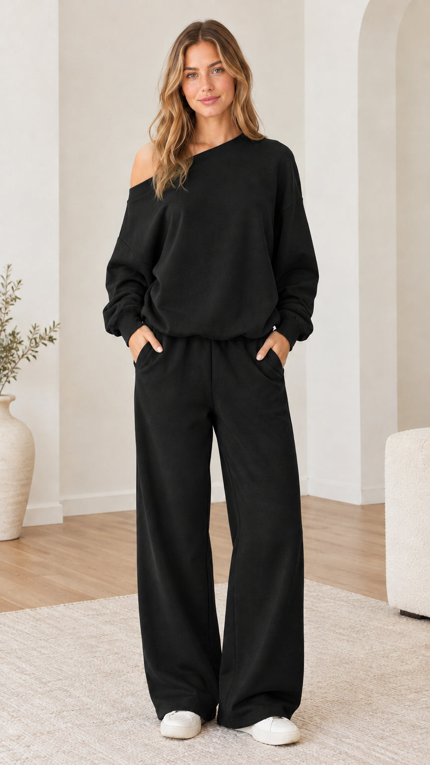 Model wearing black one-shoulder sweatshirt and wide-leg sweatpants set