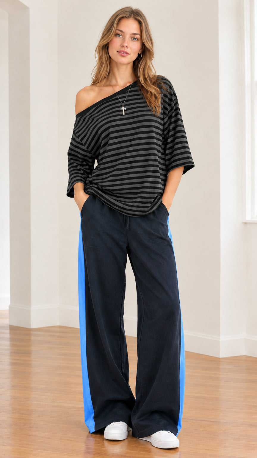 Model wearing black and charcoal striped one-shoulder top paired with side-stripe wide-leg pants
