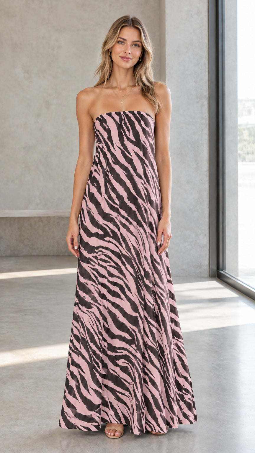 Front view of model wearing pink and black zebra print strapless maxi dress