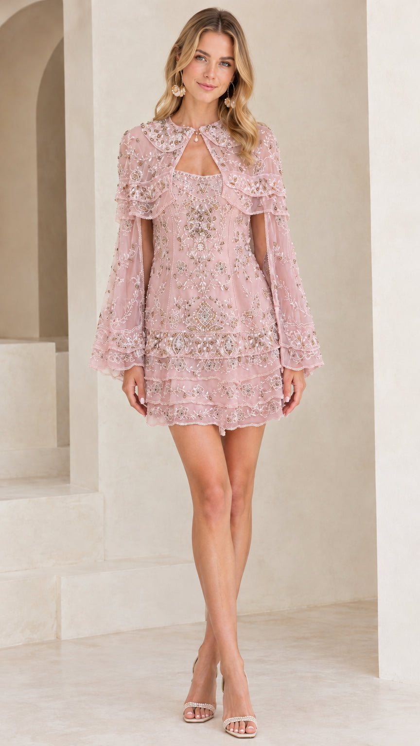 Front view of model wearing blush pink beaded capelet mini dress
