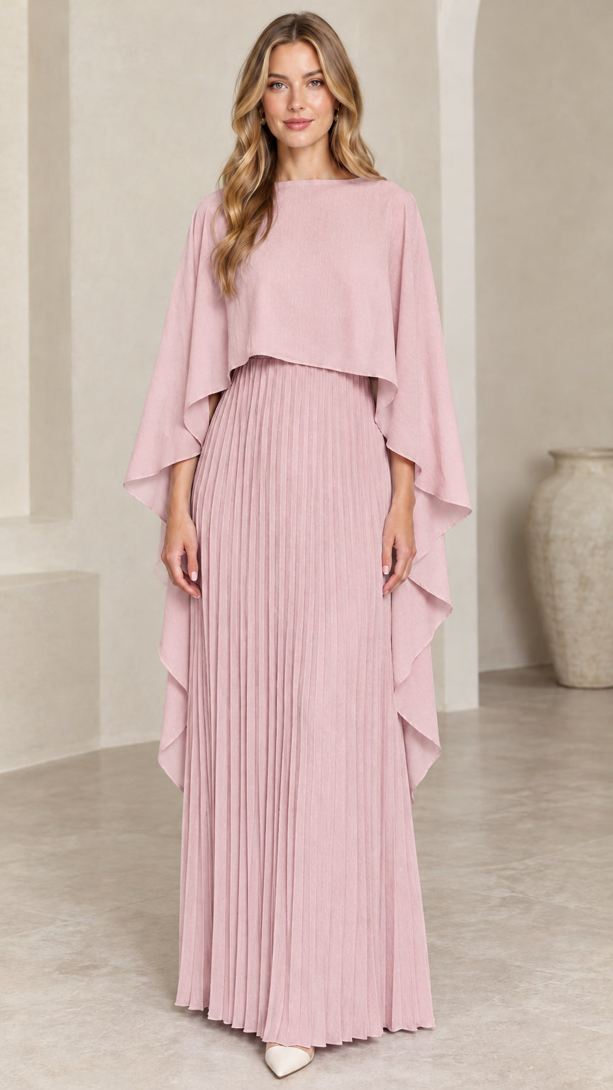 Front view of woman wearing dusty pink pleated cape maxi dress
