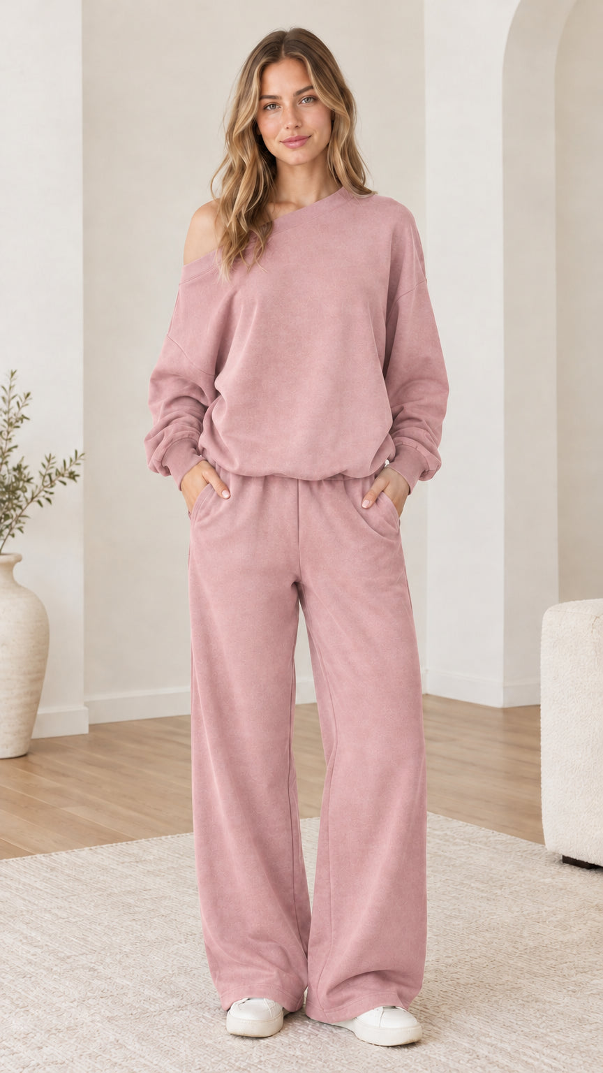 Model wearing dusty pink one-shoulder sweatshirt and wide-leg sweatpants set