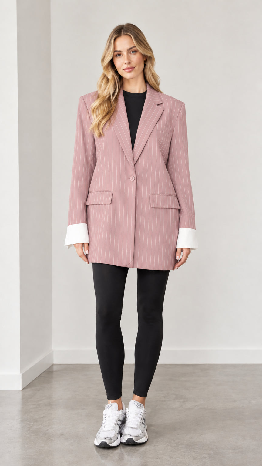 Front view of woman wearing dusty pink pinstripe oversized blazer with white cuffs
