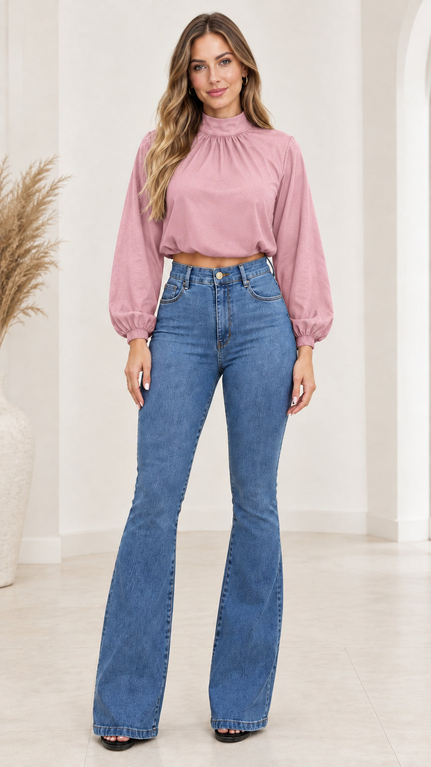 Front view of model wearing dusty pink high-neck crop blouse paired with blue flare jeans