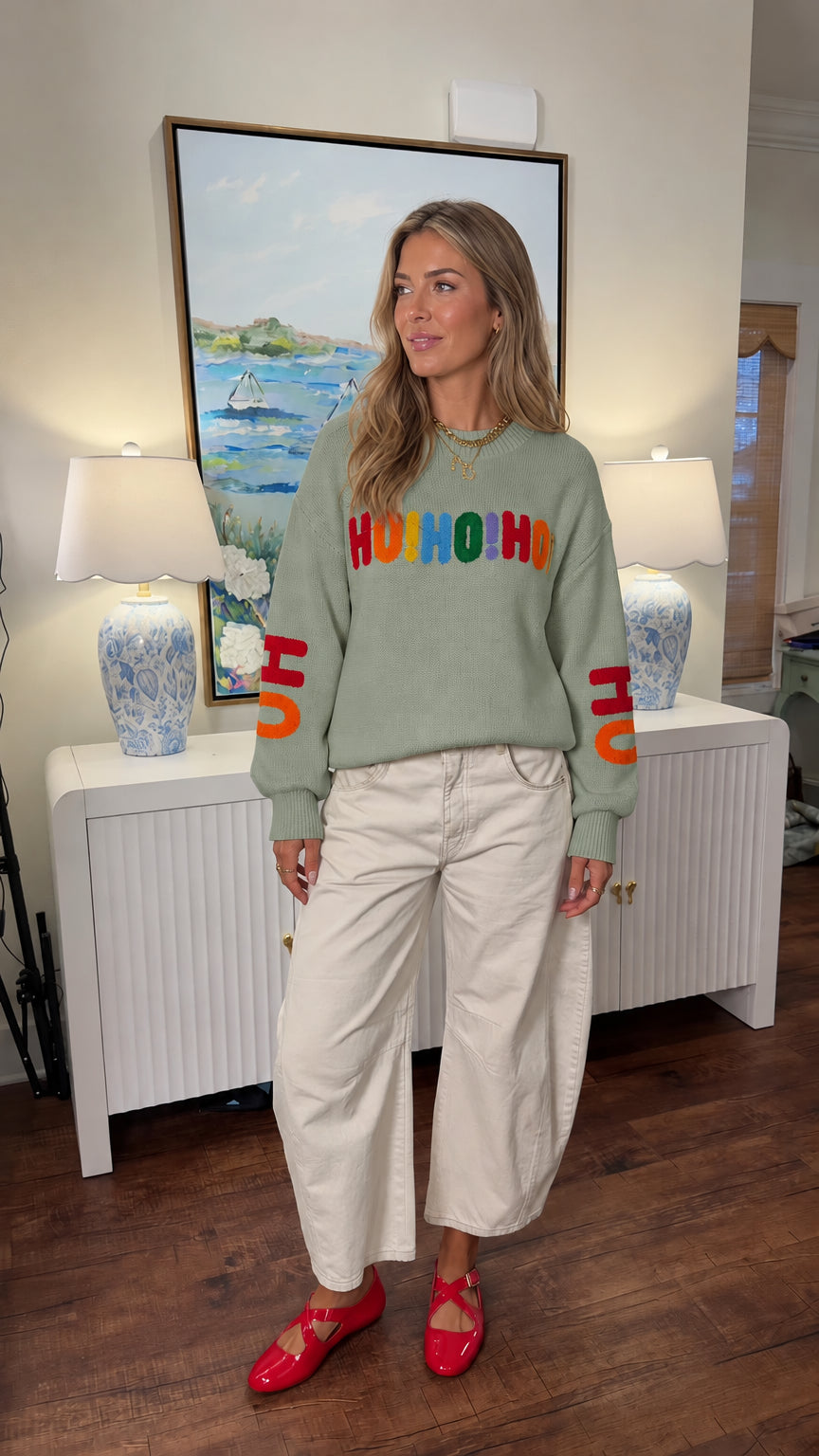 Woman wearing sage green Ho Ho Ho graphic knit holiday pullover
