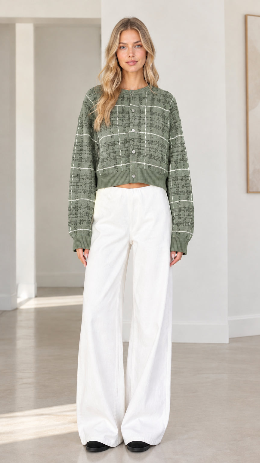 Front view of woman wearing sage green plaid cropped cardigan sweater with white wide-leg trousers