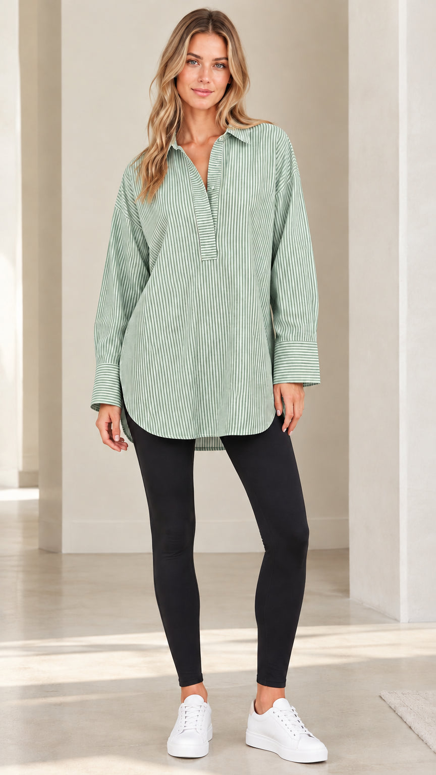 Front view of model wearing sage green and white vertical striped popover tunic shirt