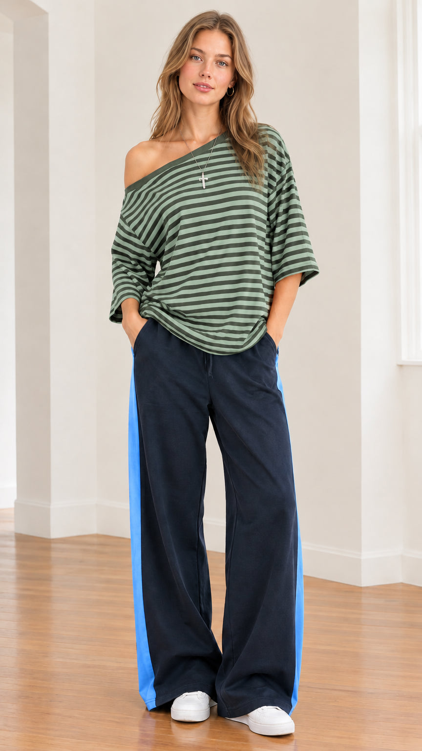 Model wearing sage green striped one-shoulder top with relaxed navy and green stripe pants