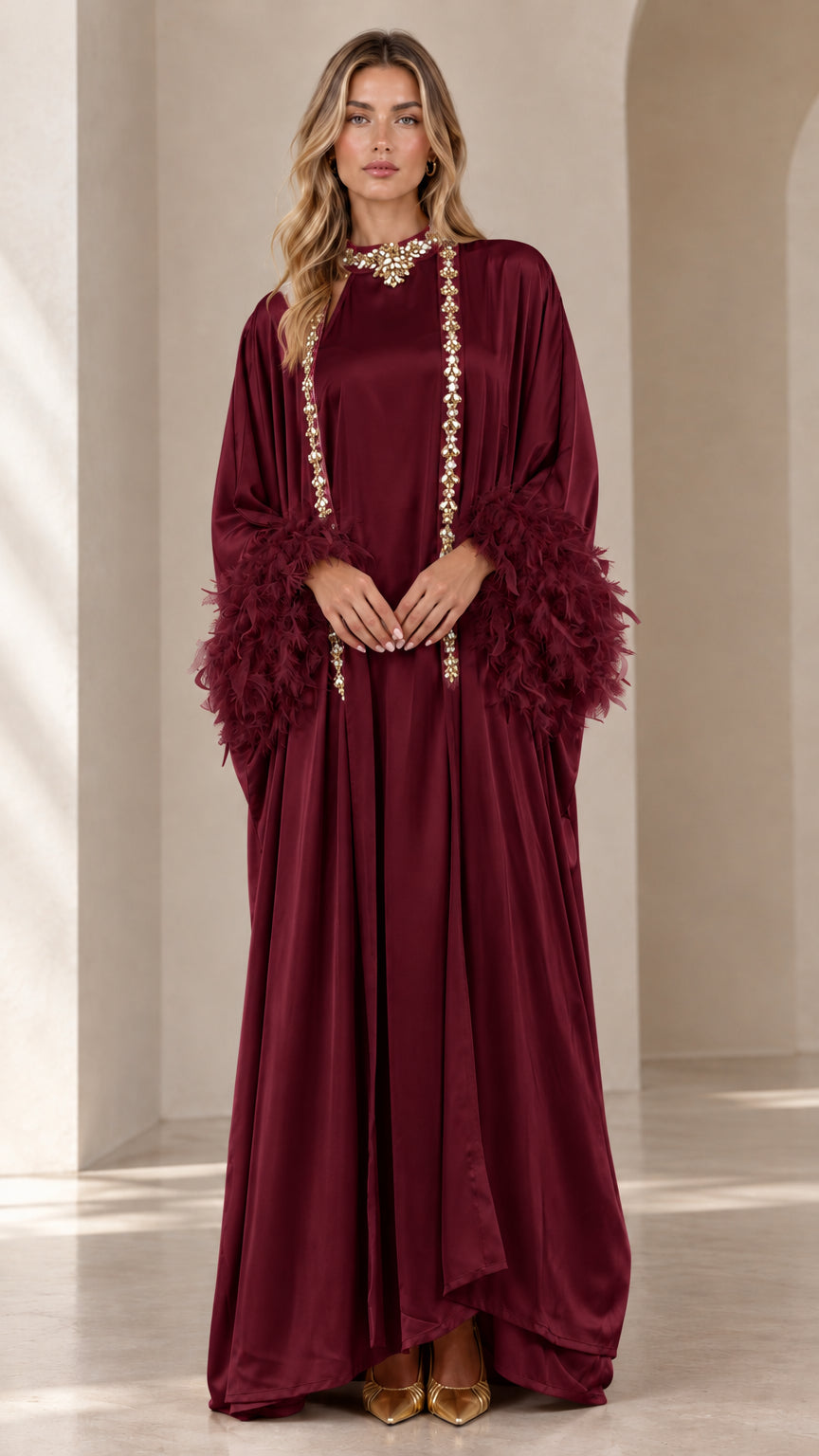 Front view of woman wearing burgundy wine satin embellished maxi kaftan with feather cuffs
