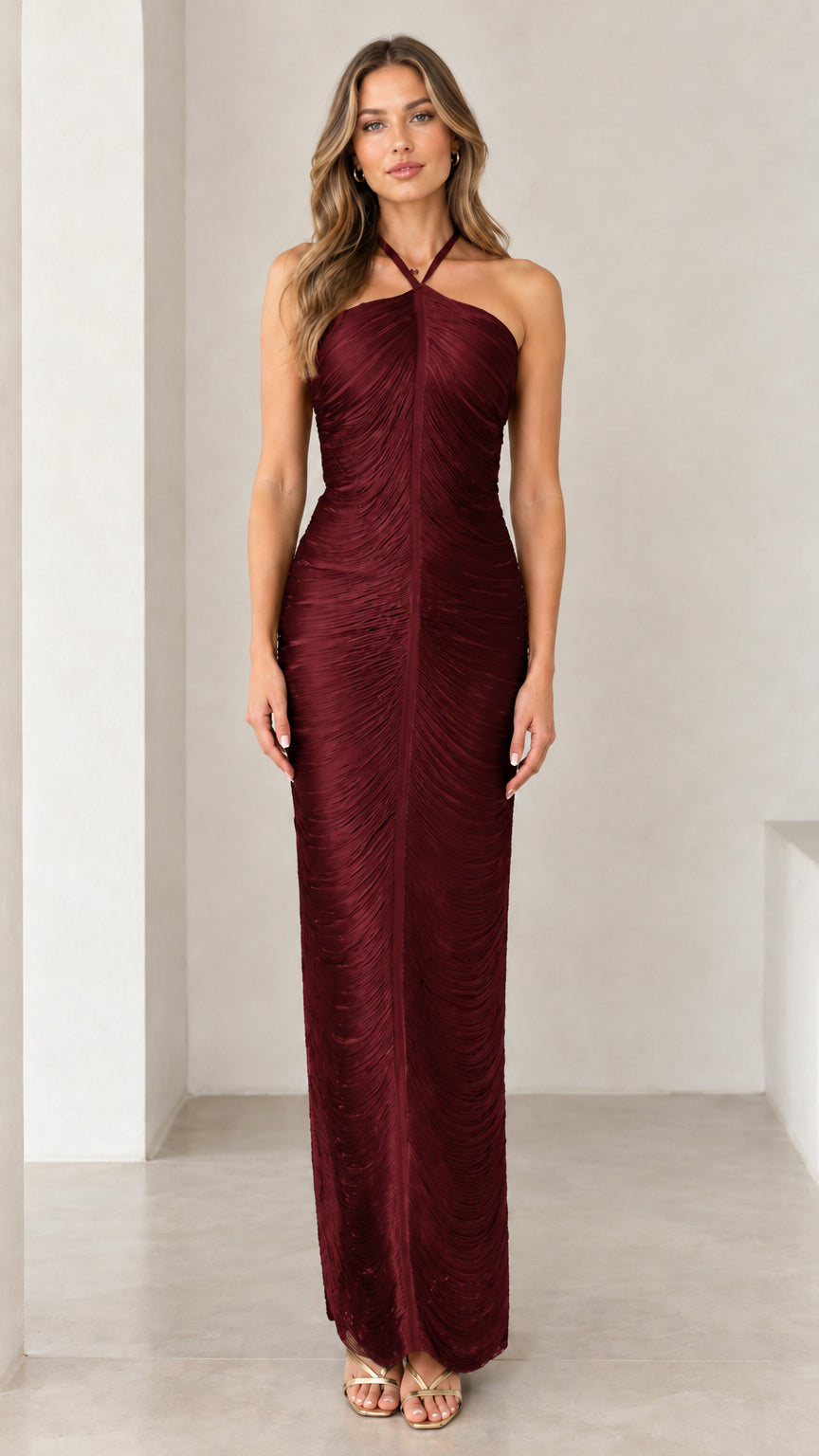 Front view of woman wearing burgundy halter ruched backless maxi dress