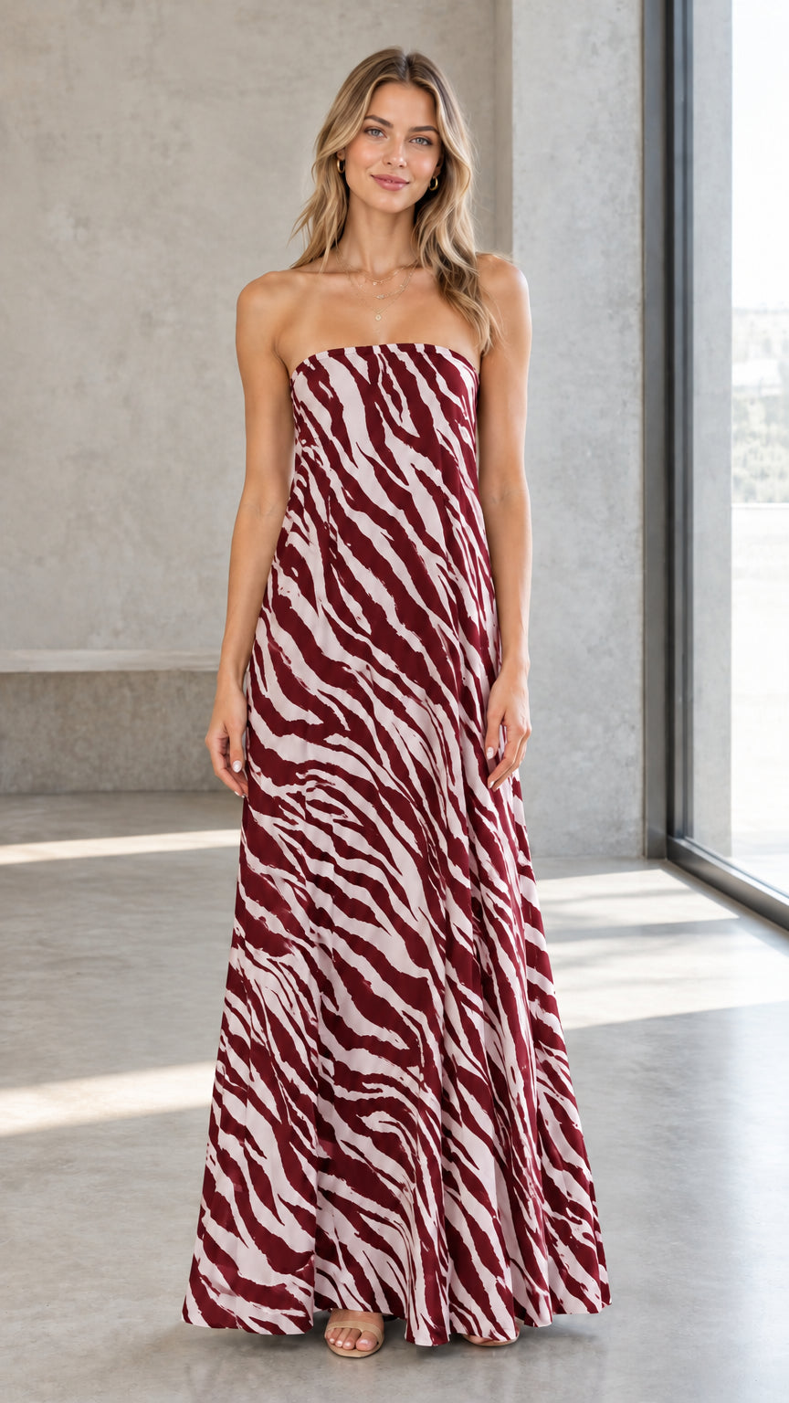 Front view of model wearing burgundy and white zebra print strapless maxi dress