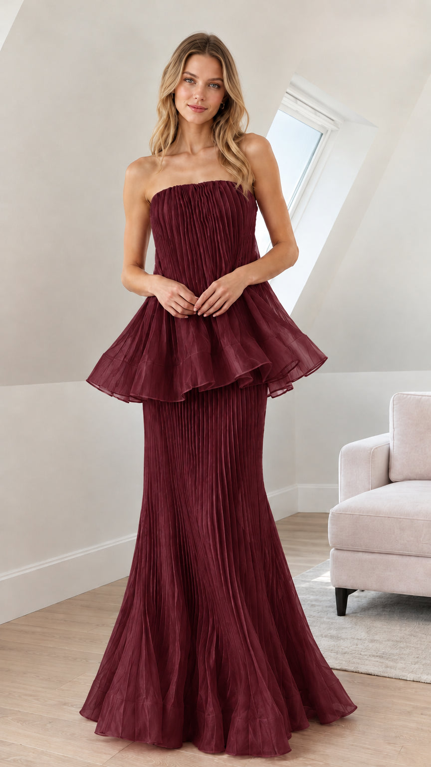 Front view of woman wearing burgundy strapless pleated peplum evening dress