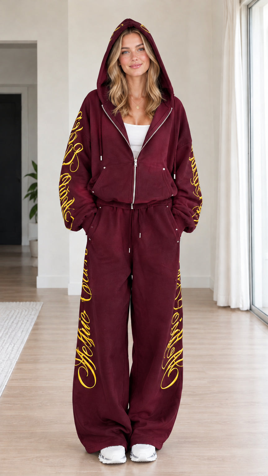 Front view of woman wearing burgundy script embroidered zip-up hoodie and wide-leg sweatpants set
