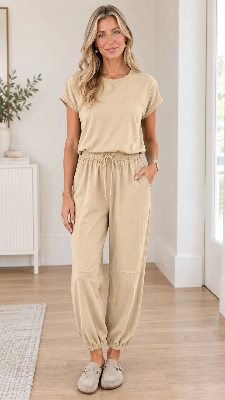 Front full view of woman wearing beige short sleeve casual jogger jumpsuit