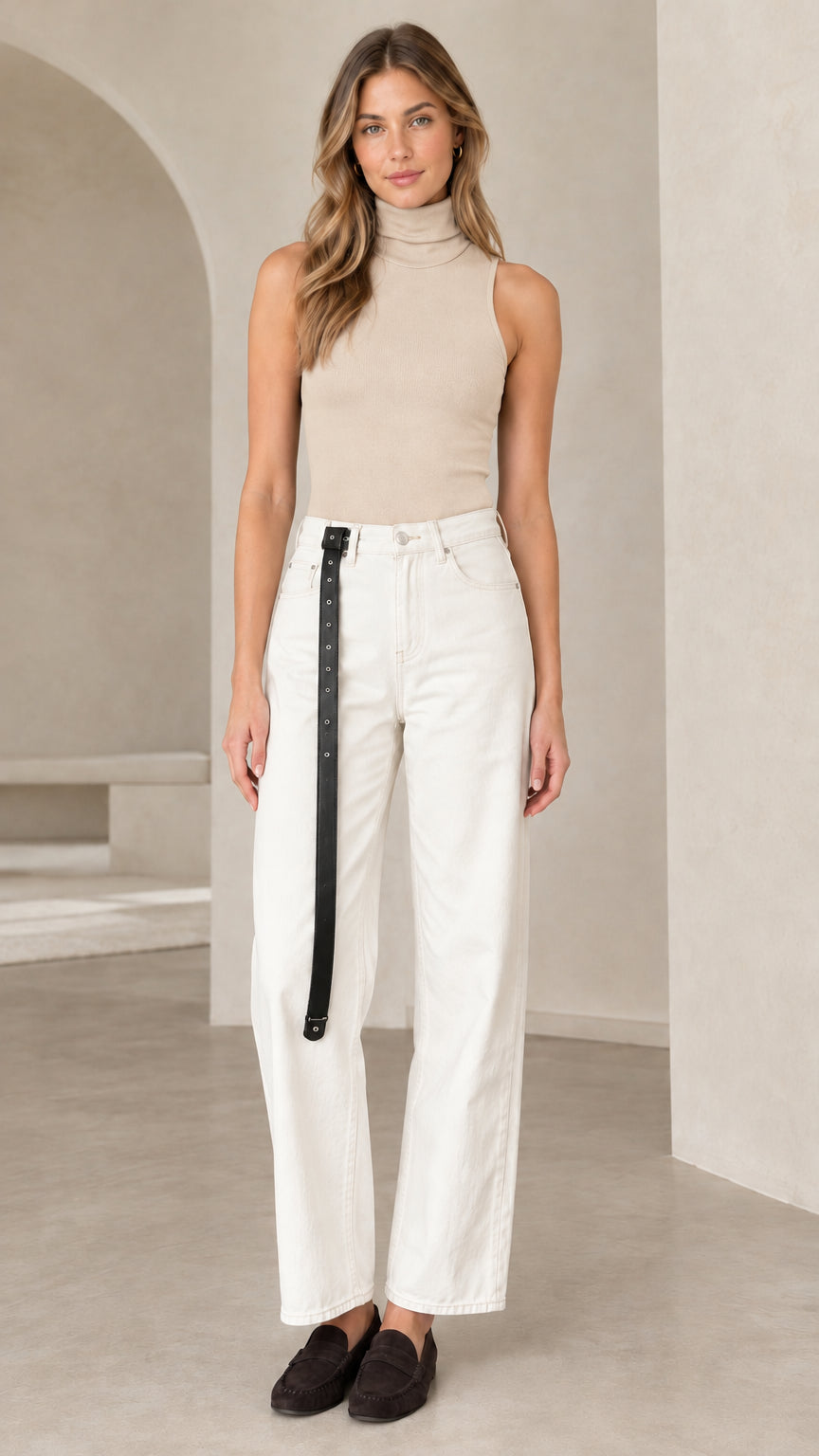 Front view of woman wearing beige sleeveless mock turtleneck top with white wide-leg trousers