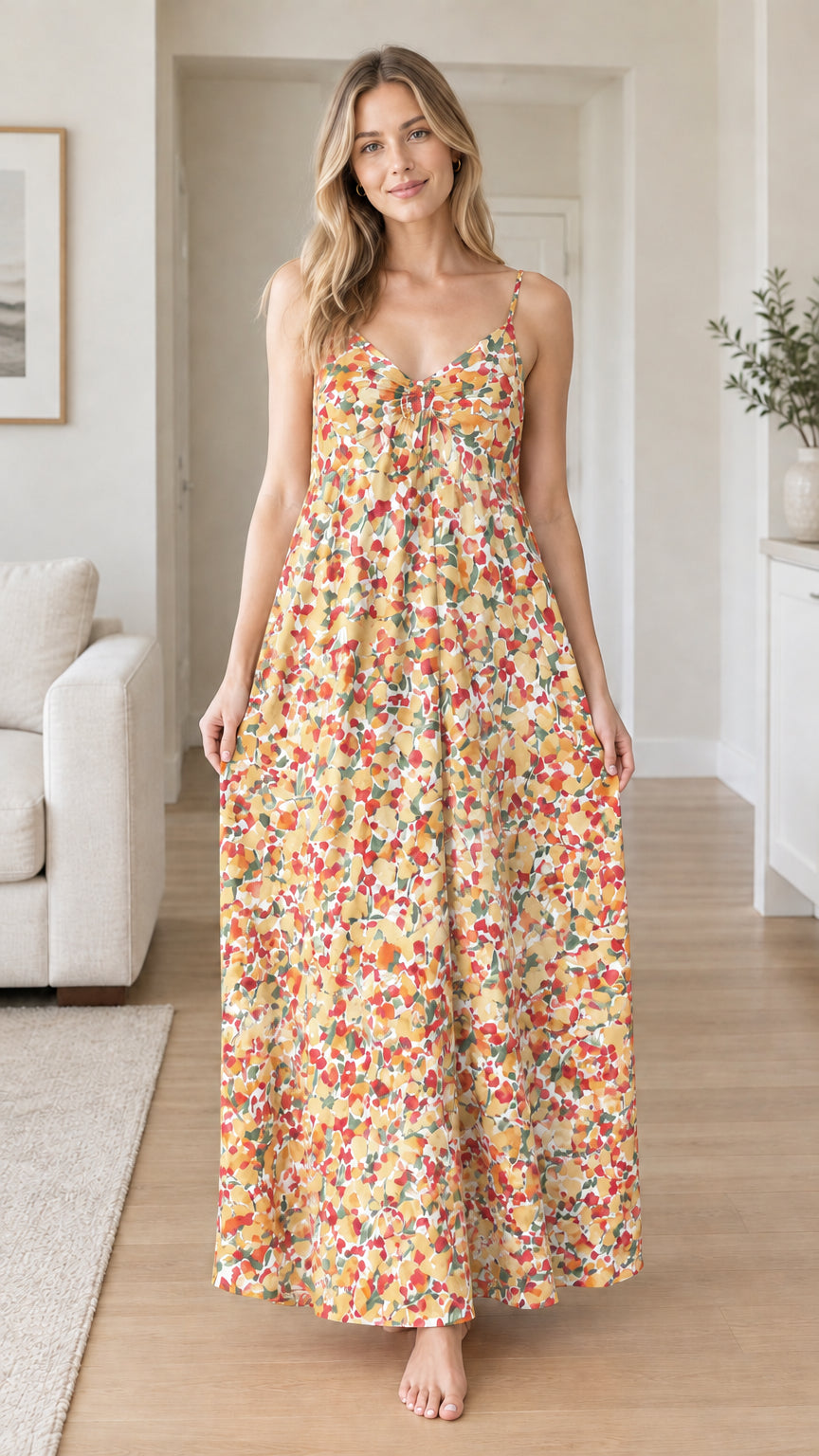 Front view of woman wearing yellow floral spaghetti strap backless maxi dress