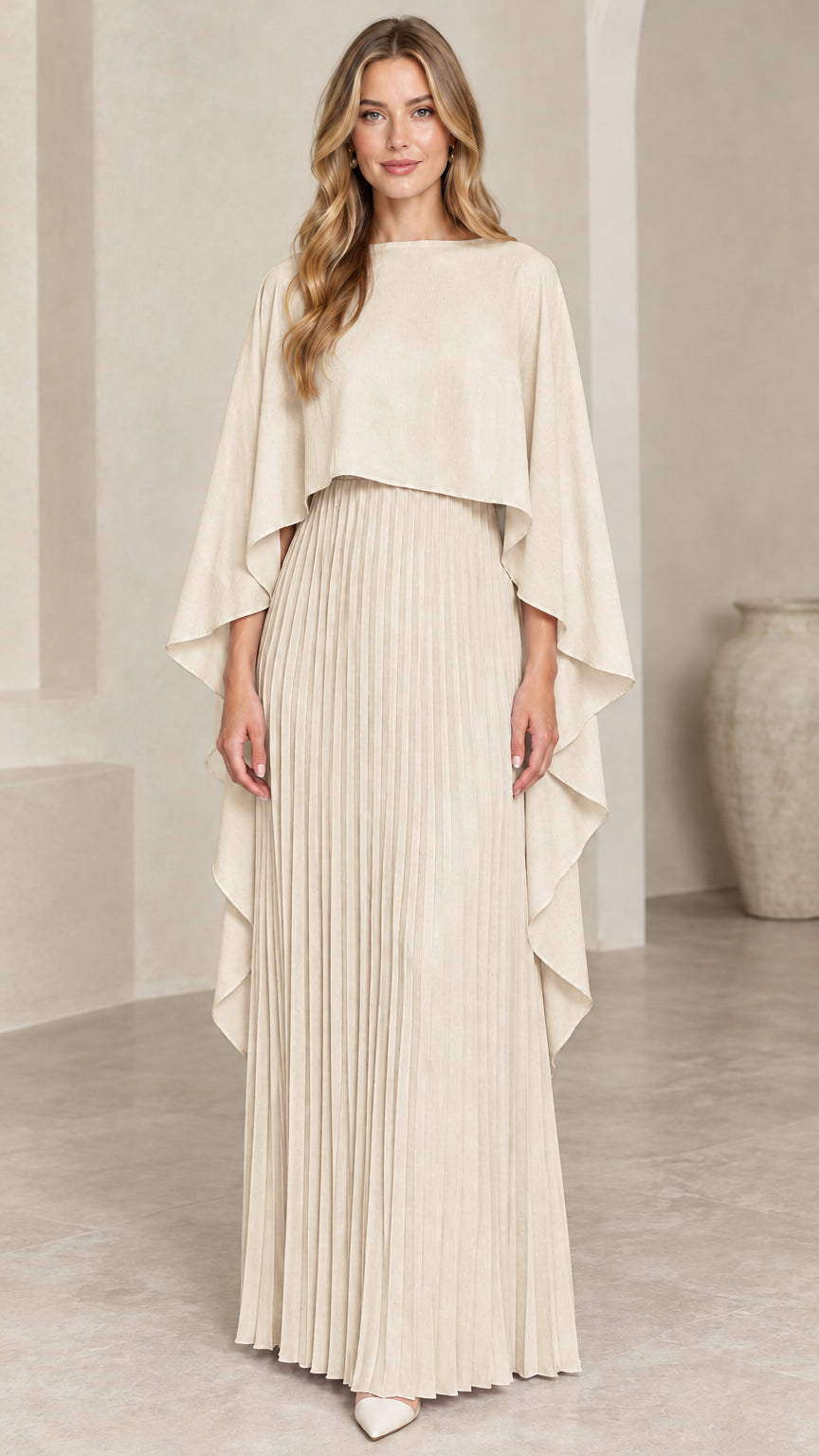 Front view of woman wearing champagne beige pleated cape maxi dress