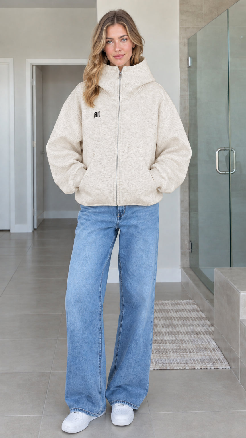 Front view of model wearing oatmeal beige oversized high-neck zip-up fleece hoodie jacket