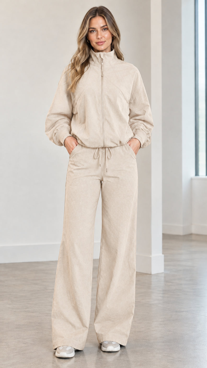 Front full view of woman wearing beige cream zip-up track jacket and matching wide-leg pants