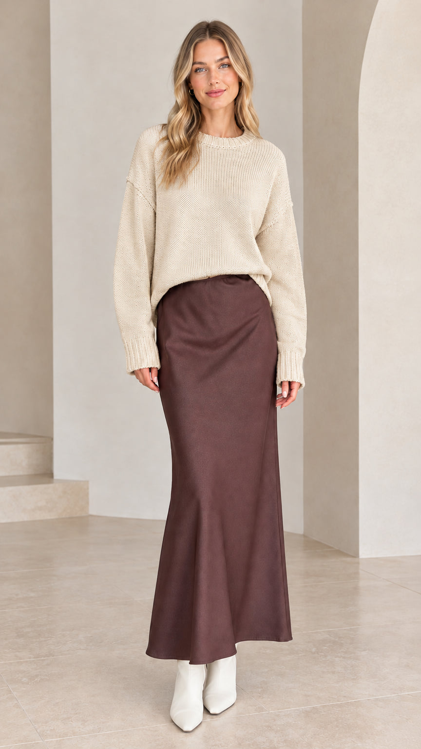 Model wearing beige drop shoulder relaxed knit sweater with brown satin skirt