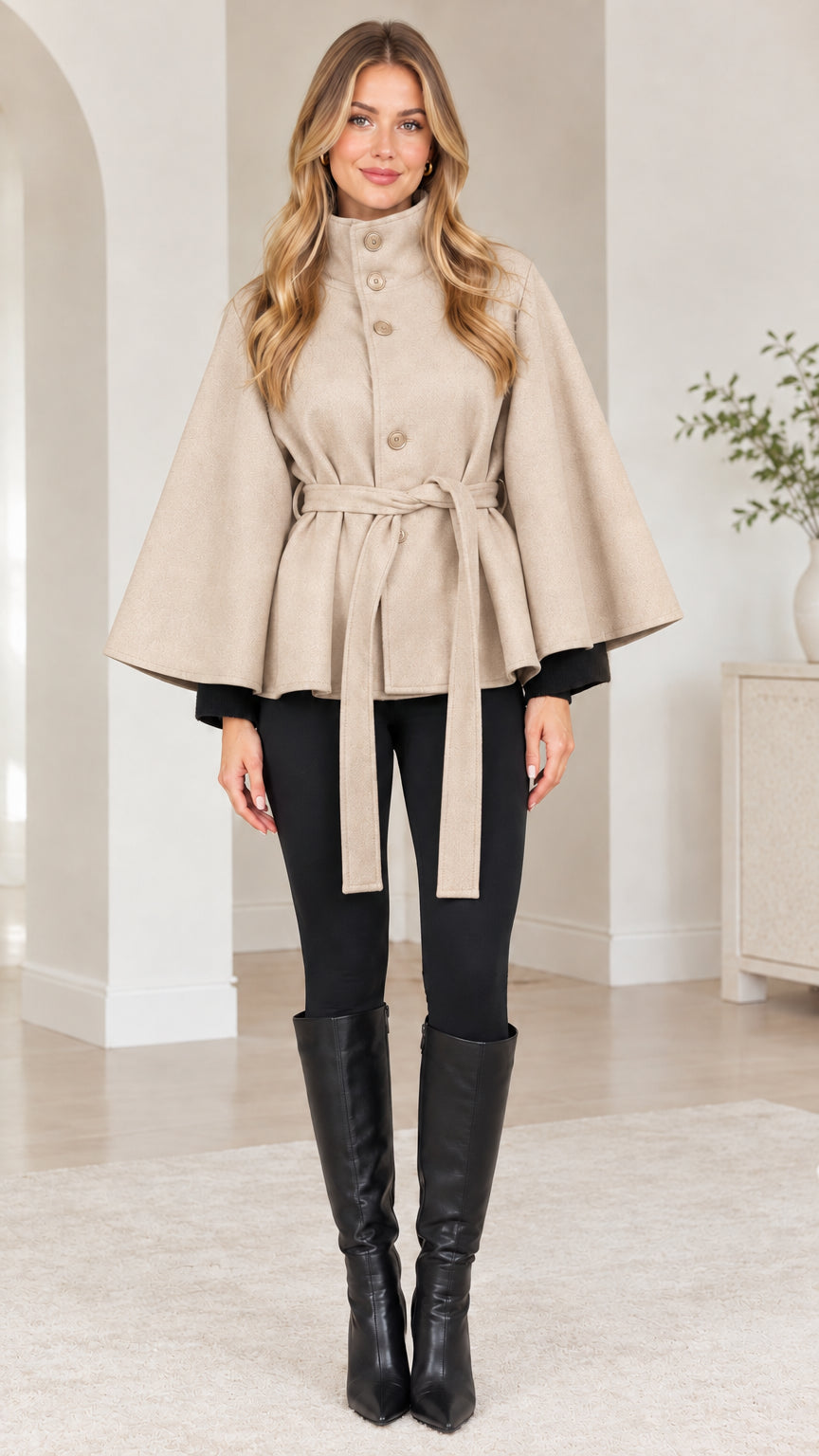 Front view of woman wearing beige cream belted cape coat with matching belt