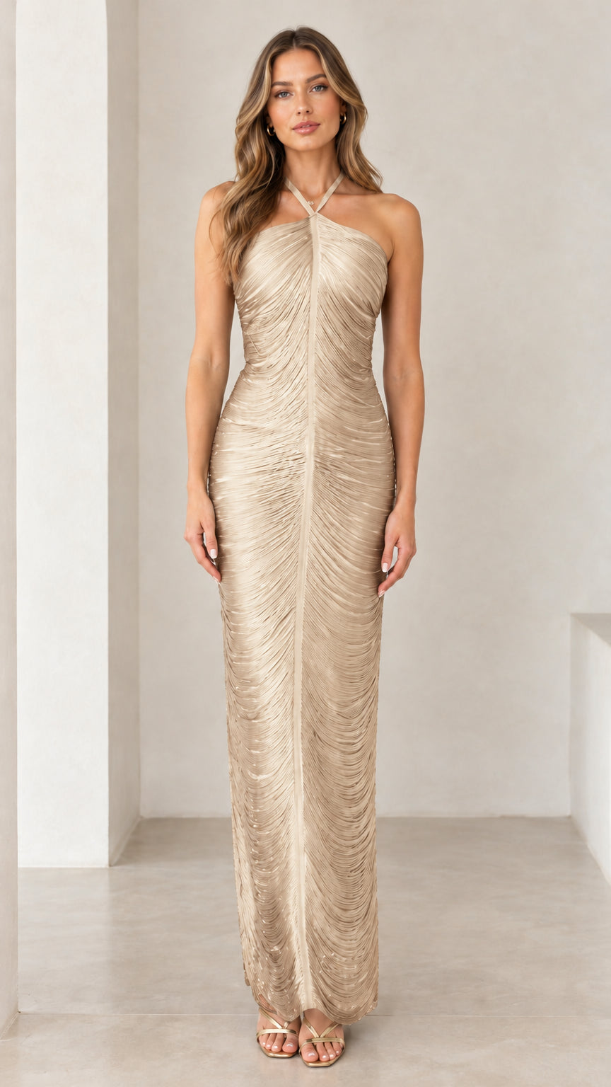 Front view of woman wearing champagne gold halter ruched backless maxi dress