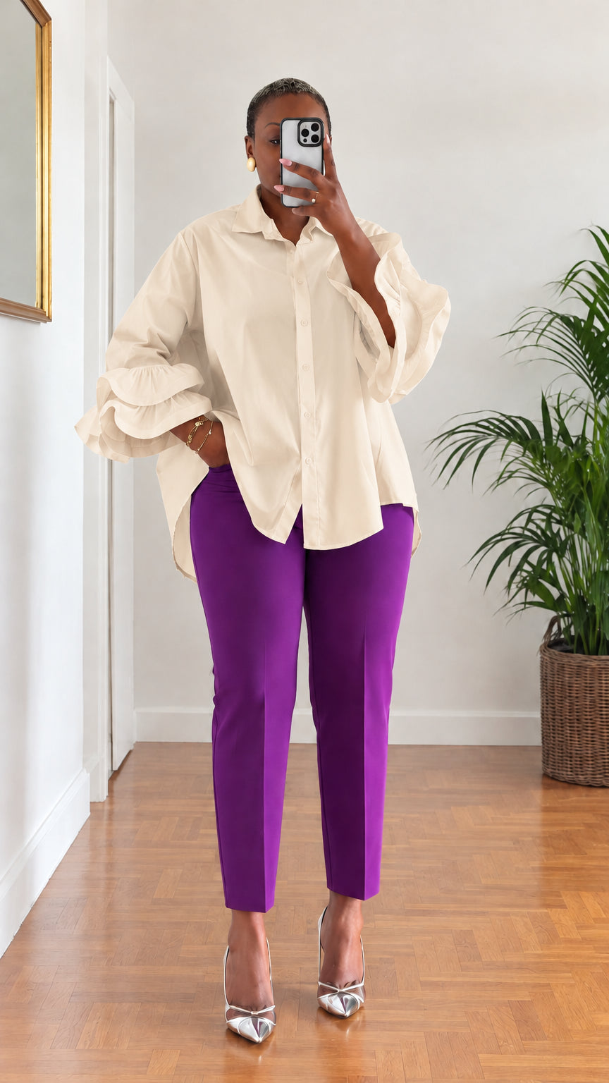 Full-length view of woman wearing cream beige tiered ruffle sleeve collared blouse with purple trousers
